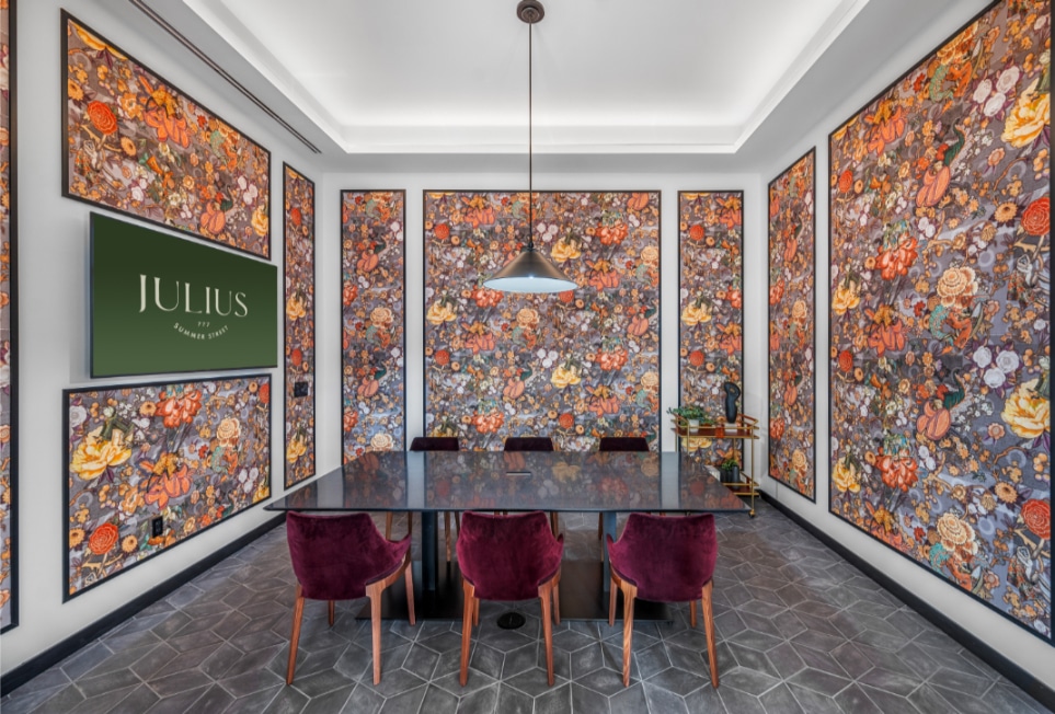 Vibrant conference room with colorful floral art panels, a black table, and plush burgundy chairs, creating a dynamic atmosphere.