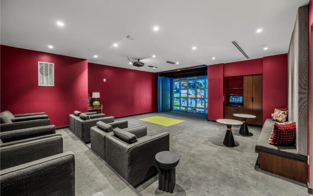 Theater room with dark grey seating, red walls, and a large screen setup for an immersive viewing experience.