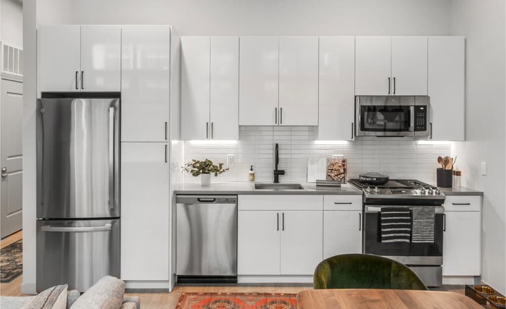 Close-up view of a modern kitchen featuring sleek white cabinets, stainless steel appliances, and under-cabinet lighting