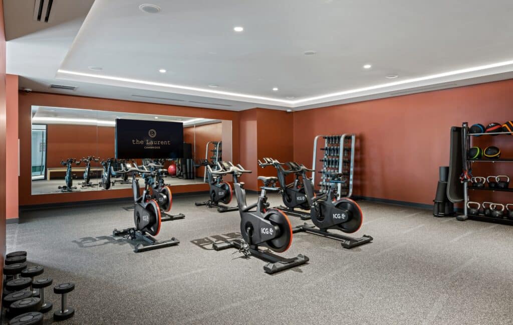 Spin studio with mirrored walls, stationary bikes, and weights, set against warm, earthy-colored walls.